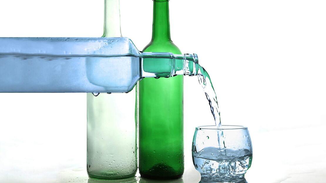 Verschiedene Wasserflaschen und ein Wasserglas