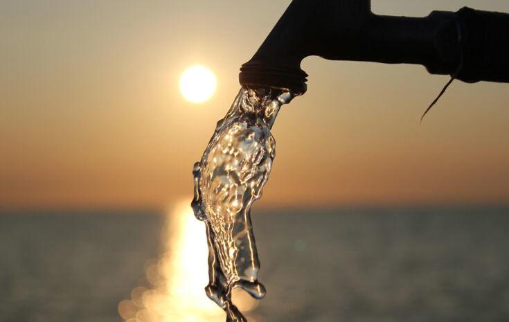 Wasser fließt aus einem Wasserhahn im Sonnenuntergang