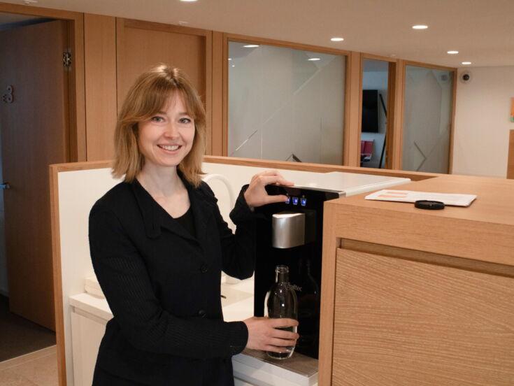 Vera Klein von acrevis befüllt Wasserflasche am Wasserspender CUBE Compact