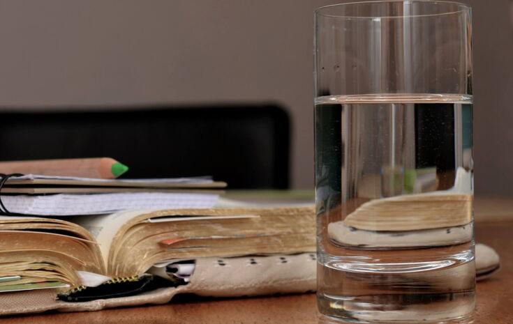 Ein Buch und ein Glas Wasser auf einem Tisch