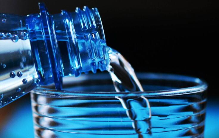 Wasser aus Plastikflasche in Glas eingießen