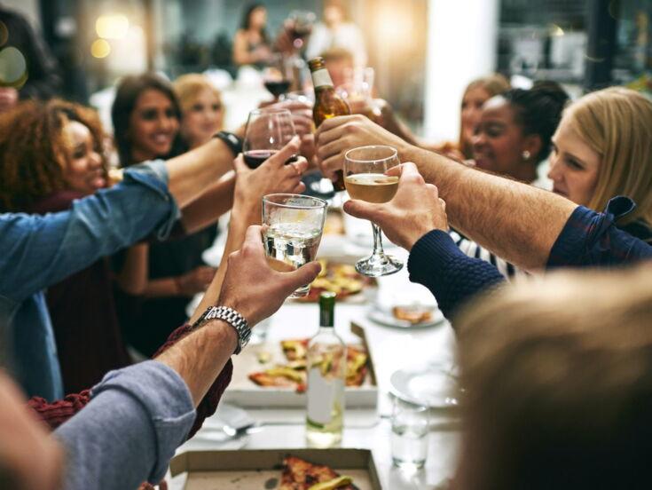 Menschen stoßen mit Getränken an beim Essen