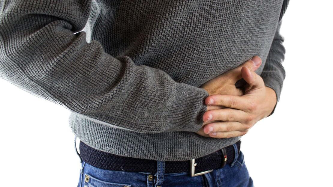 Ein Mann hält seinen Bauch und hat Schmerzen