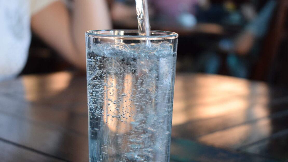 Ein sprudelndes Wasserglas was auf einem Holztisch steht