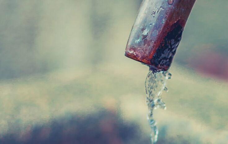Wasser tropft aus einem Hahn in einen Brunnen
