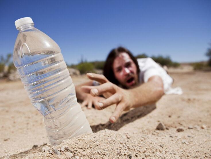 Mann greift nach Wasserflasche im Sand