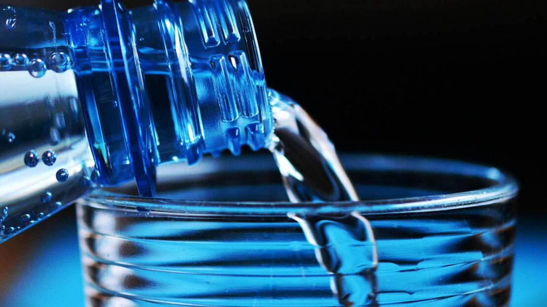 Wasser aus Plastikflasche in Glas eingießen
