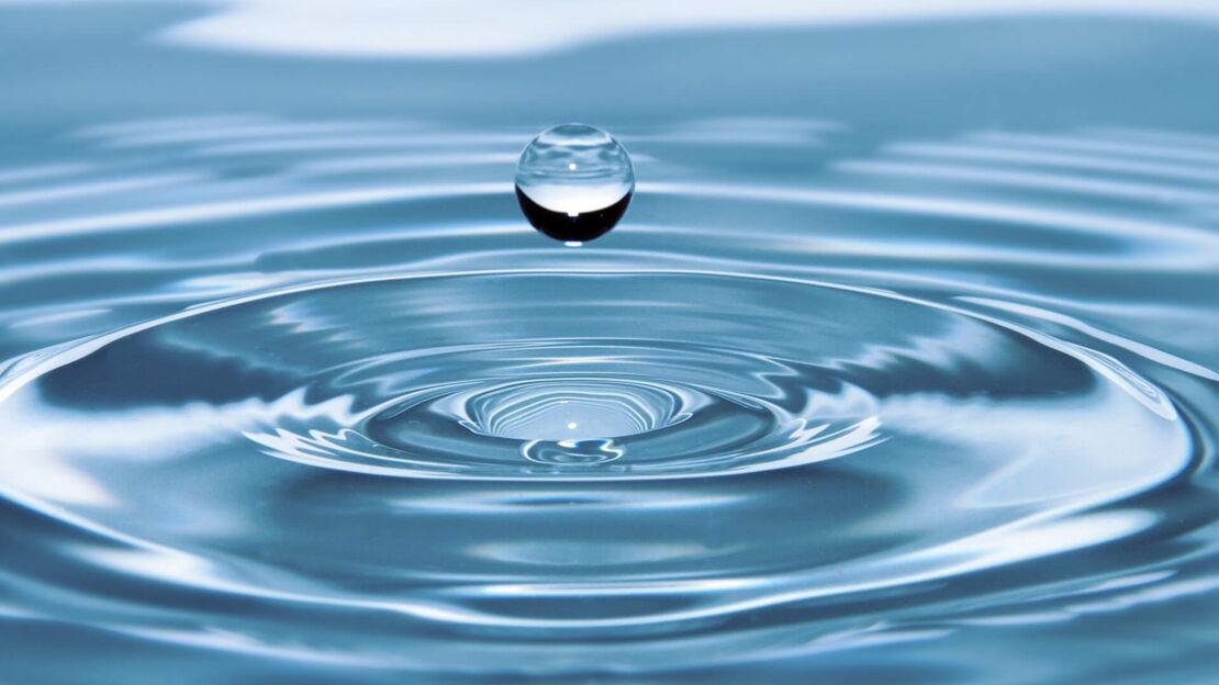 Frei schwebender Wassertropfen über einer Fluessigkeit