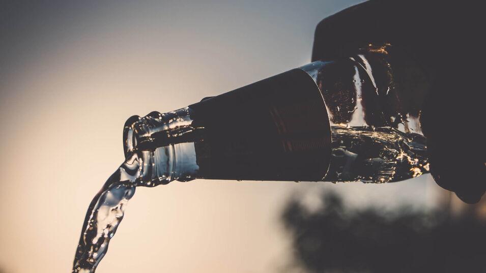 Ausgießen einer Glasflasche im Sonnenuntergang