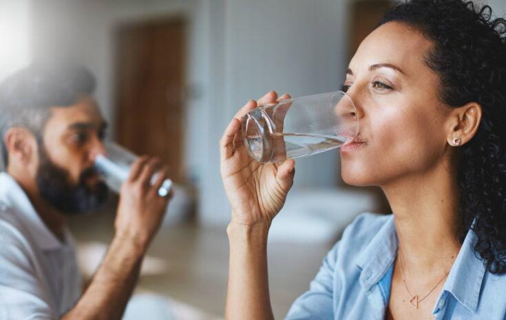 Frau und Mann trinken Wasser aus einem Glas
