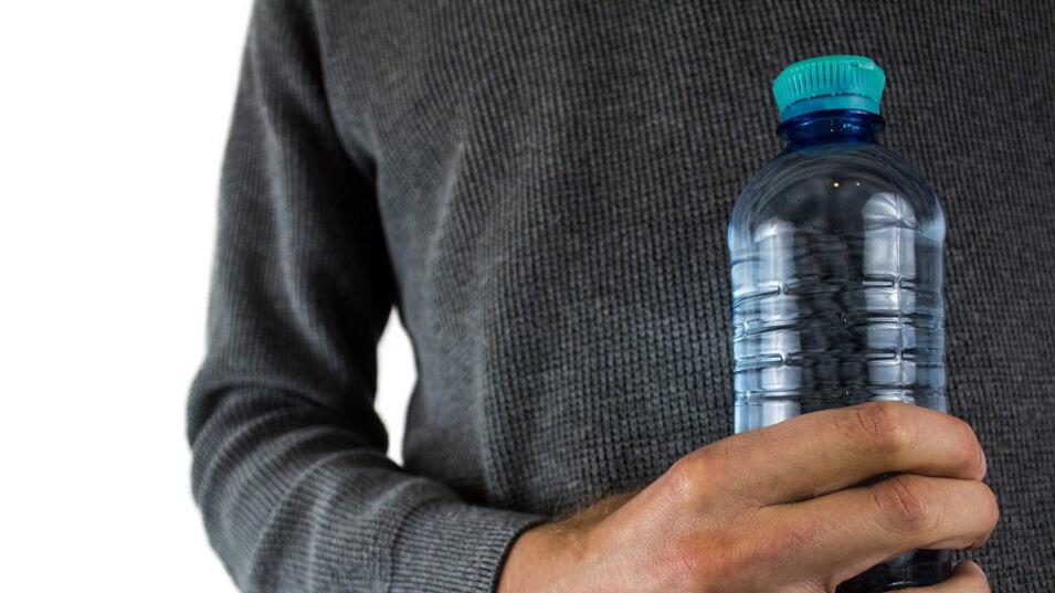 Mann mit gefüllter Plastikflasche in der Hand