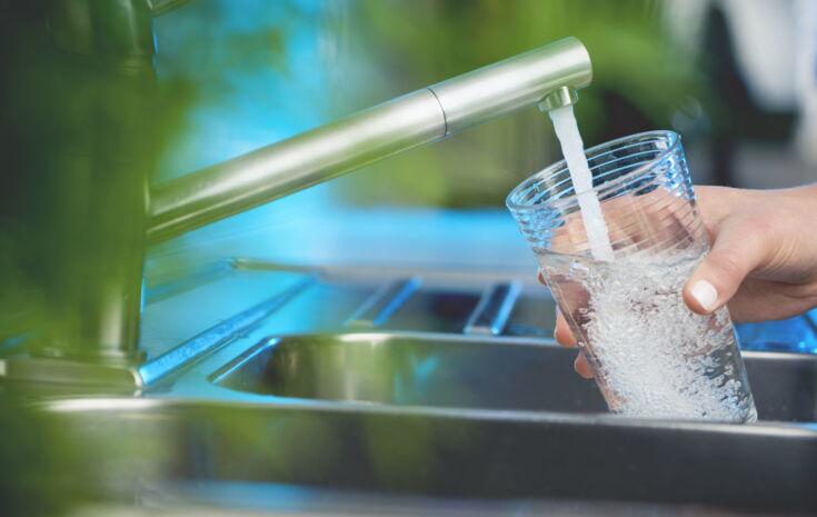 Wasser aus dem Wasserhahn fließt in ein Glas