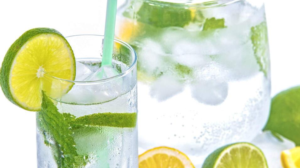 Volle Karaffe und volles Wasserglas mit Limette