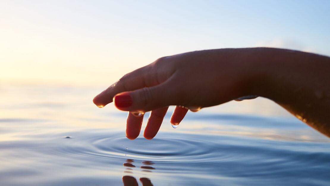 Hand berührt das Wasser