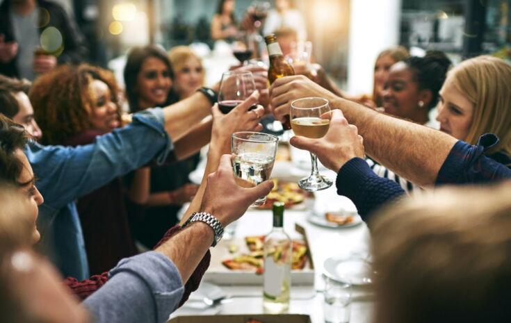 Menschen stoßen mit Getränken an beim Essen