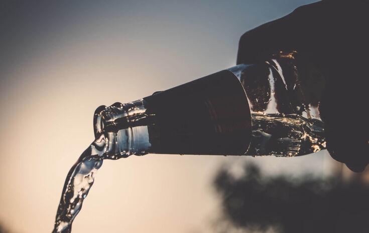 Ausgießen einer Glasflasche im Sonnenuntergang