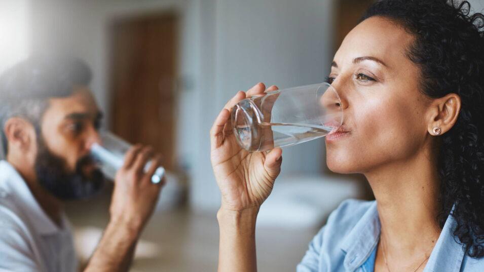 Frau und Mann trinken Wasser aus einem Glas