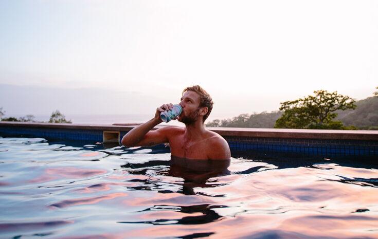 Mann trinkt Wasser im Pool