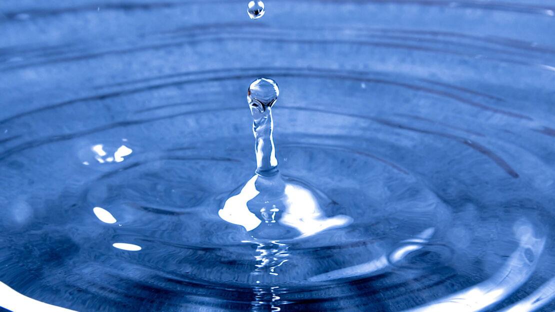 Ein blauer Wassertropfen auf einer Wasseroberfläche
