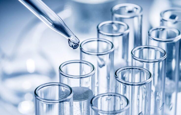 Pipette mit Wassertropfen und Reagenzgläsern