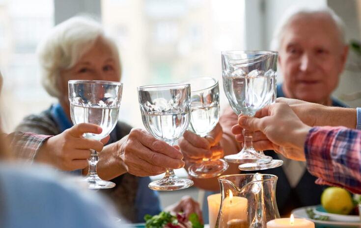 Eine Familie sitzt am Tisch und stößt mit Wasser an