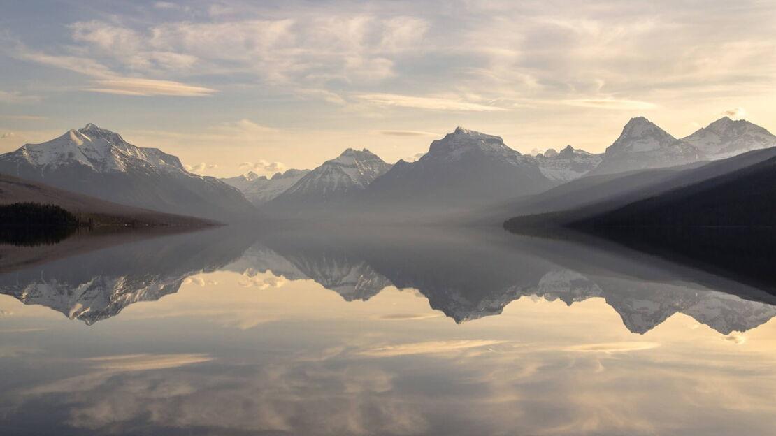 Gebirge spiegelt sich in glatter Wasseroberfläche