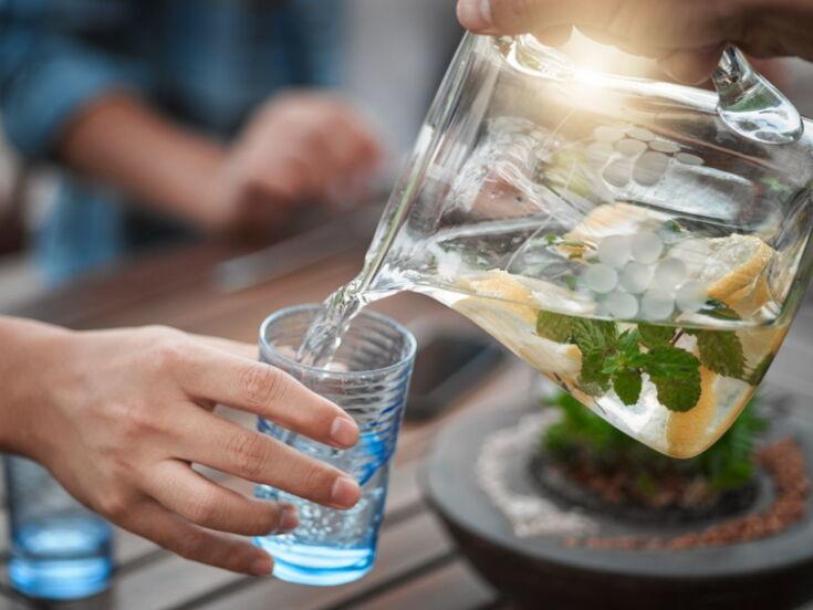 Wasser aus einer Wasserkaraffe wird in Wasserglas gegossen