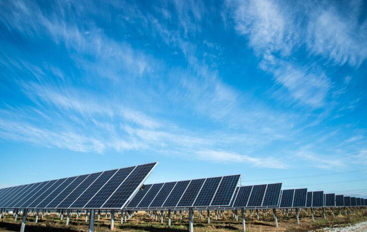 Viele Solaranlagen auf einem Feld bei Sonnenschein und blauem Himmel