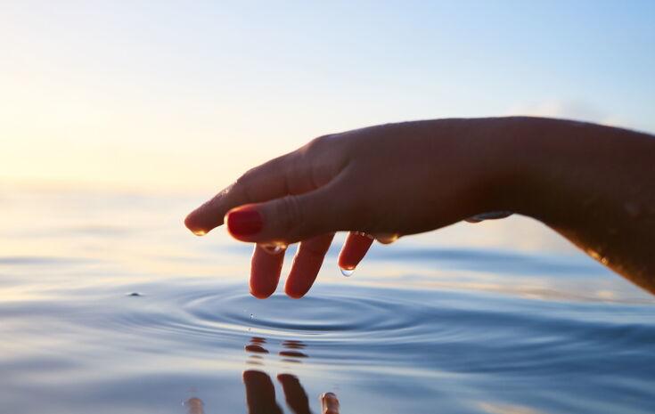 Hand berührt das Wasser