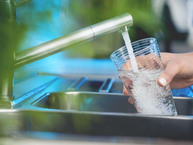 Wasser aus dem Wasserhahn fließt in ein Glas