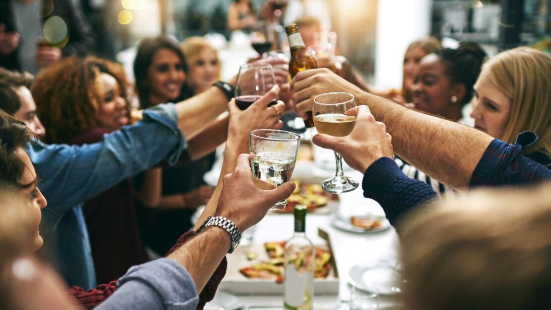 Menschen stoßen mit Getränken an beim Essen