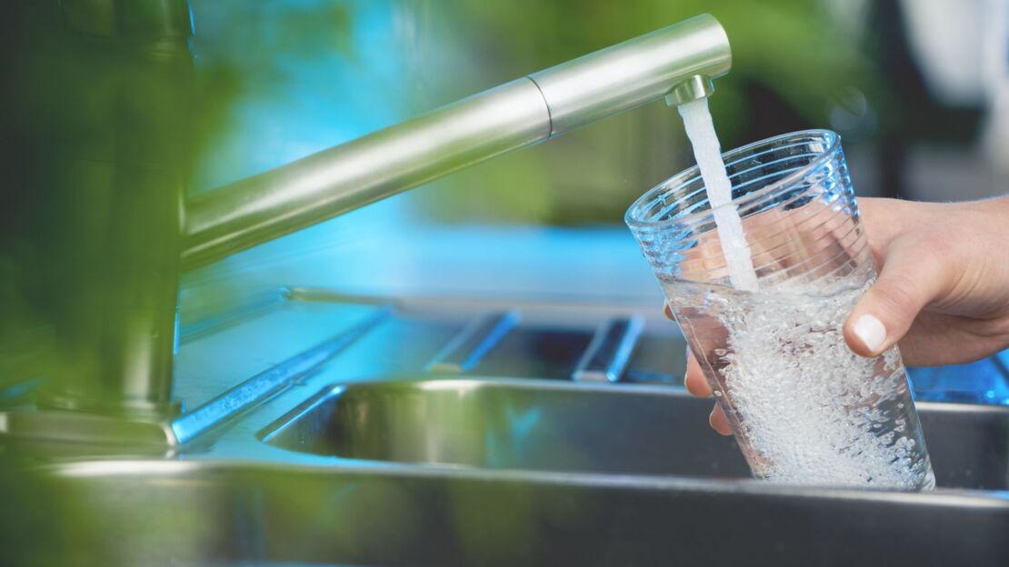 Wasser aus dem Wasserhahn fließt in ein Glas