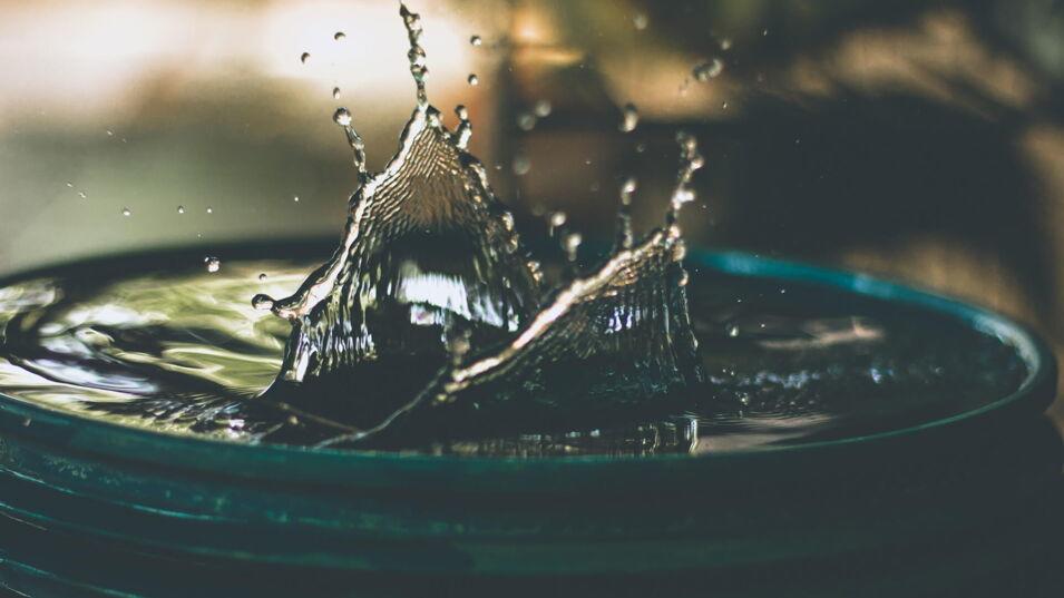 Wasser spritzt aus einem runden Behaelter nach oben